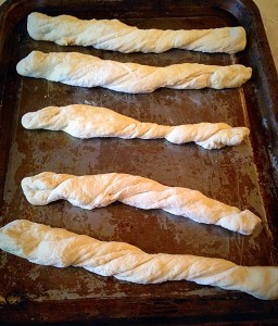 Twist each length of dough, pulling as you do so, to make a long twisted, uncooked bread stick and place on an oiled baking sheet.