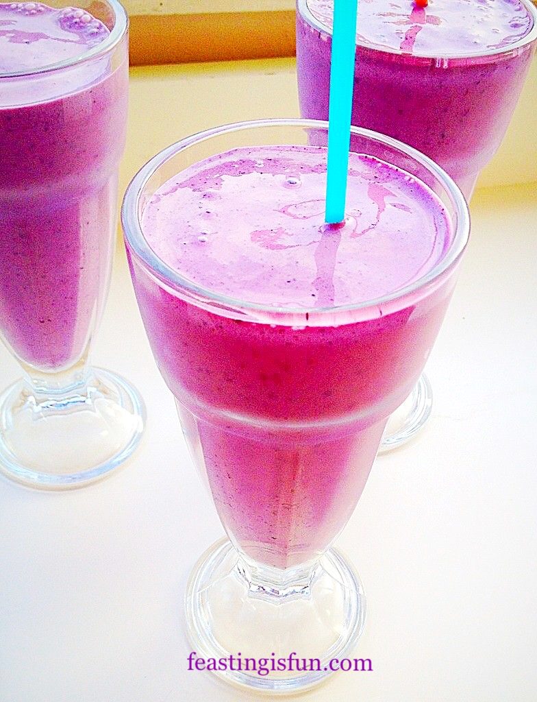 Three glasses filled with naturally coloured vivid purple blueberry banana superfood smoothies.