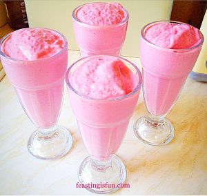 Tall glasses filled with candy pink raspberry and banana ice cream smoothies.