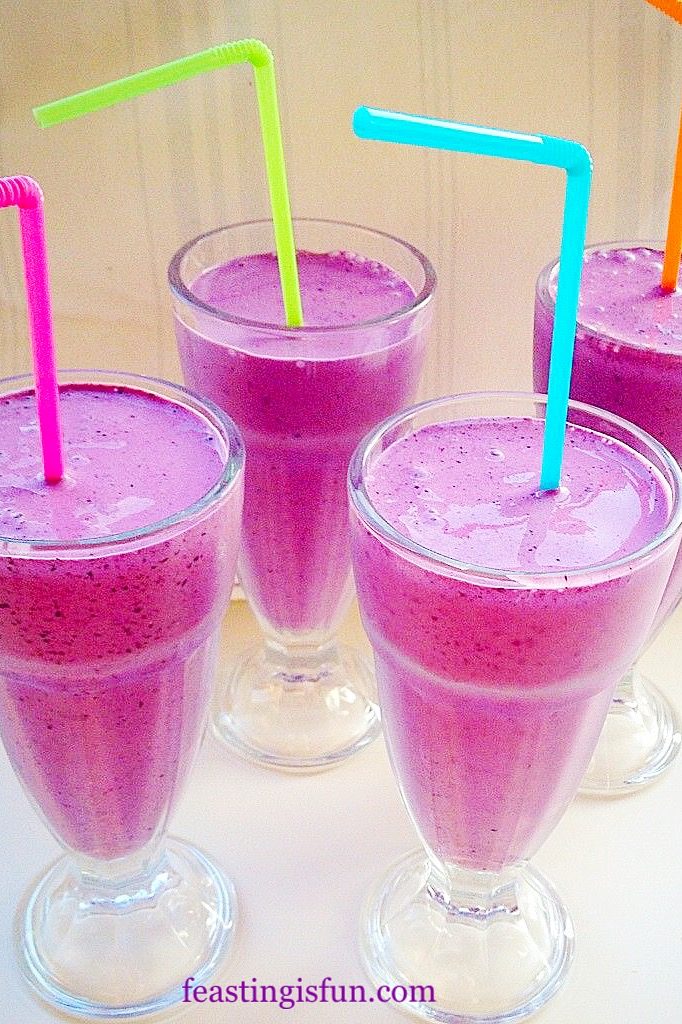 Four glasses filled with purple Blueberry Banana Superfood Smoothies.