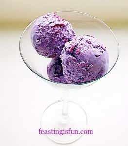 Scoops of vivid purple blueberry and gin ice Cream in a martini glass.