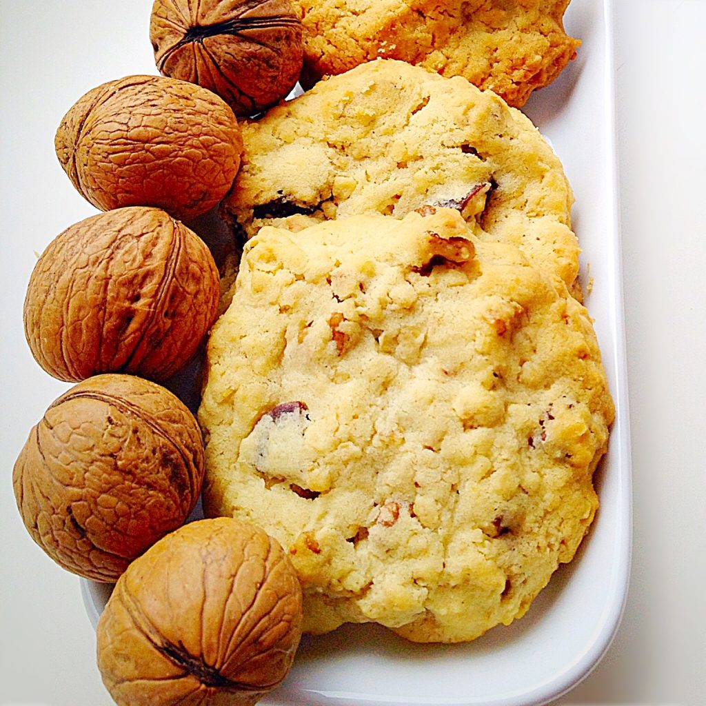 Fruit and nut biscuits on a platter with whole nuts in their shell.