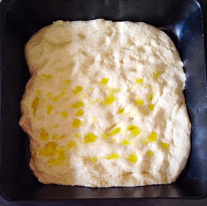 Place half of the dough in each pan. Use your fingers to make indentations all over the dough. Drizzle over some Olive oil.