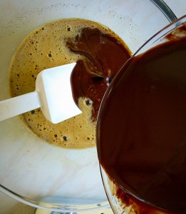 Pour the cooled chocolate mixture slowly into the bowl stirring slowly.