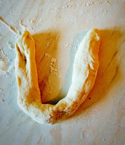 Roll a portion of dough out with your hands. Form into a horseshoe shape.