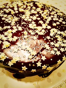 Chocolate Sparkle Cake now get sprinkling! I started with white chocolate stars and the smaller edible gold stars. www.feastingisfun.com