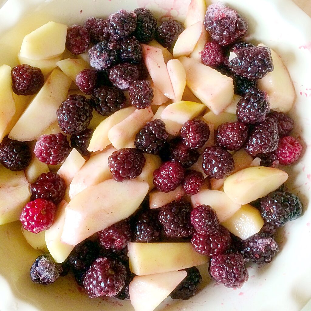 Sliced pear and frozen blackberries in a serving dish.