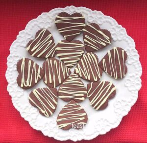 Chocolate heart shaped cookies with a white chocolate drizzle.