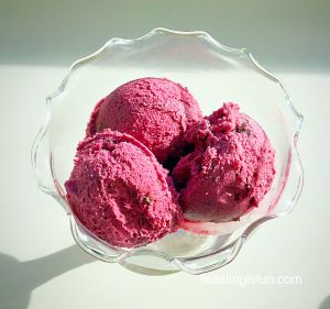Blackberry chocolate chunk ice cream scoops in a glass bowl.