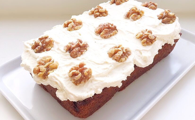 Carrot cake topped with a whipped mascarpone frosting and decorated with walnut halves.