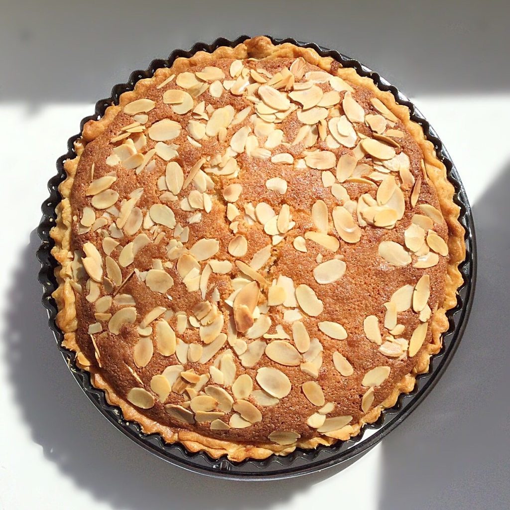 An in-iced Bakewell tart finished with flaked almonds.
