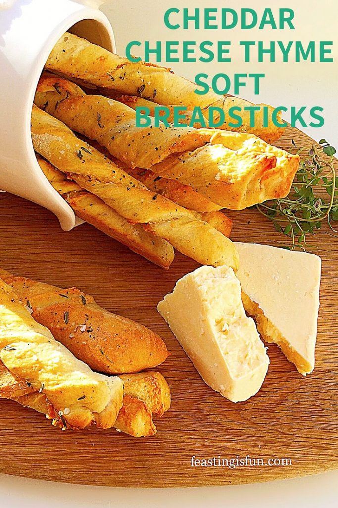 Cheddar and fresh thyme on a wooden board with breadsticks in a cream jug. Sized for Pinterest with descriptive graphics.
