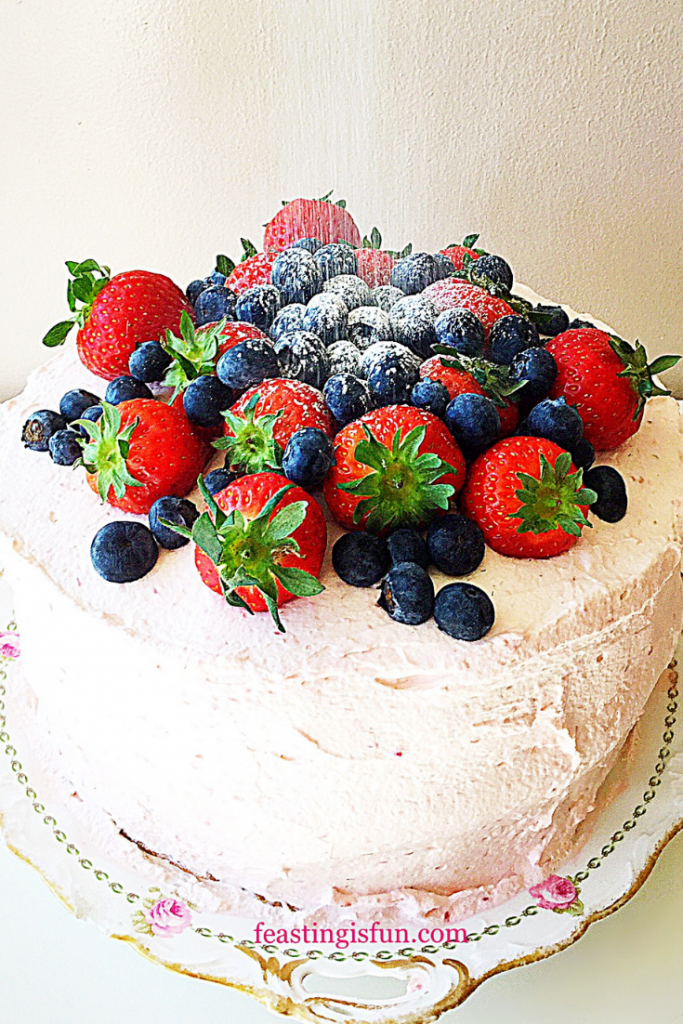 Three layer sponge cake sandwiched together with jam and raspberry whipped cream and topped with fresh berries.