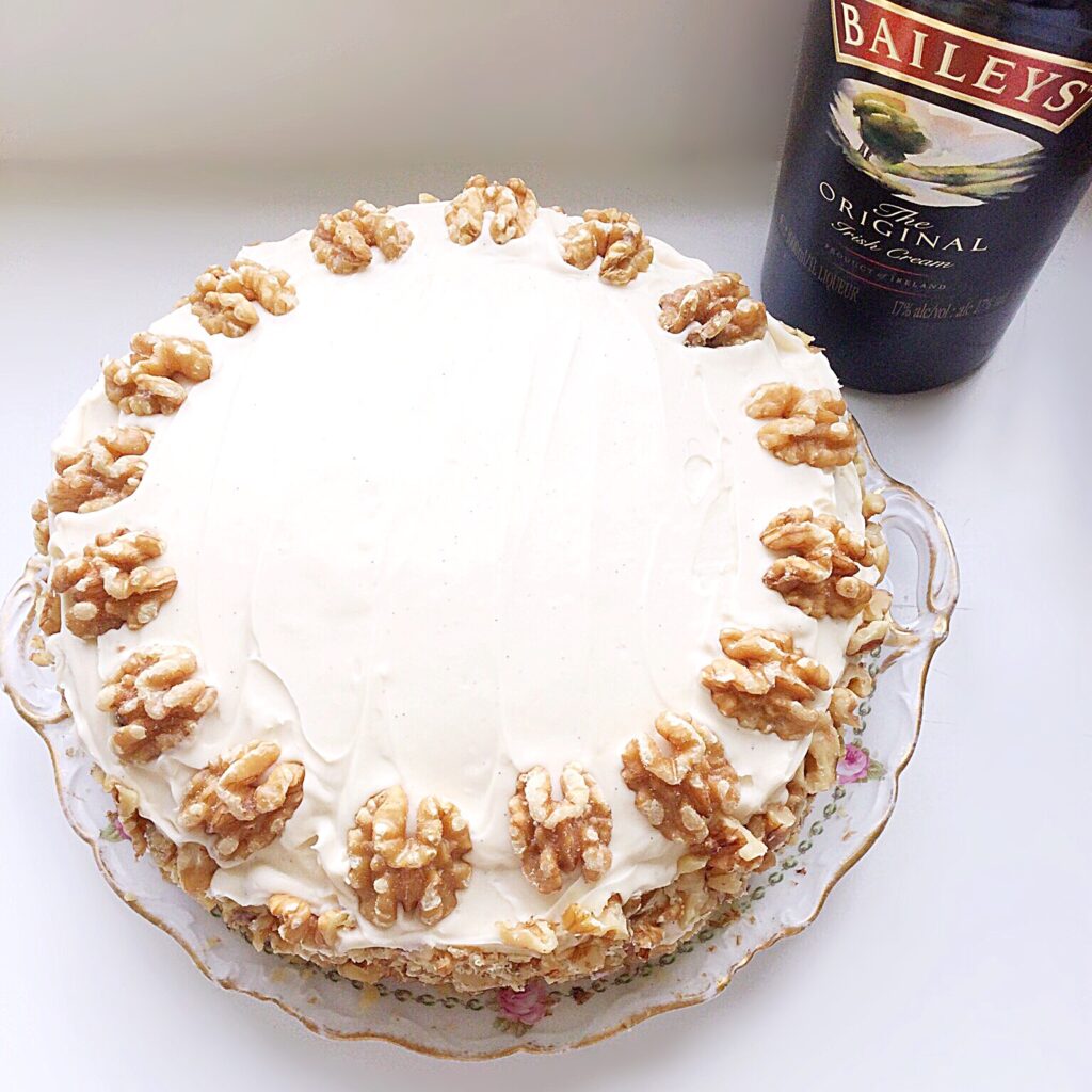 Baileys coffee cake covered in mascarpone frosting and decorated with walnuts.