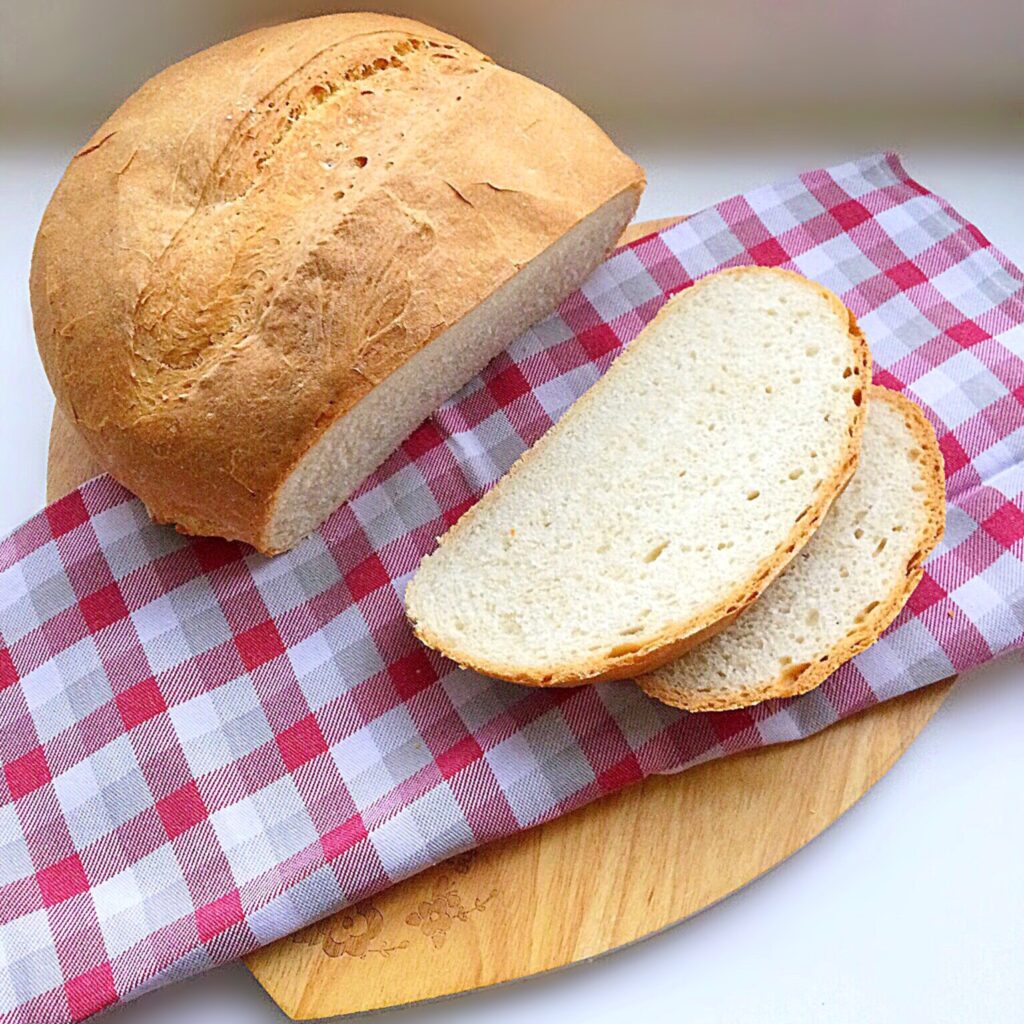 Sliced crusty white bread on a wooden board.