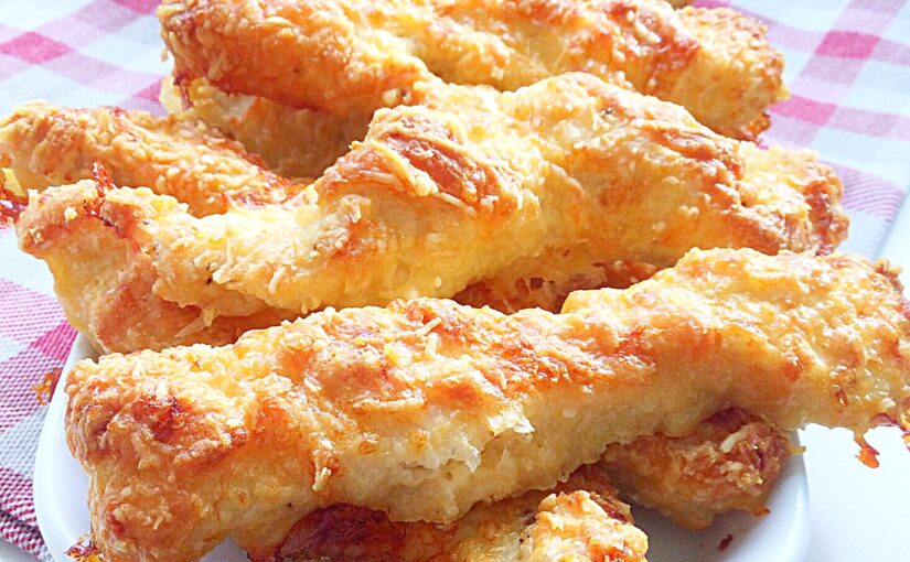 Crispy, Parmesan cheese coated golden chicken strips on a white platter.